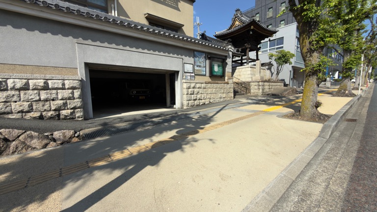 教行寺の屋内車庫と掲示板のある塀沿いの駐車スペース